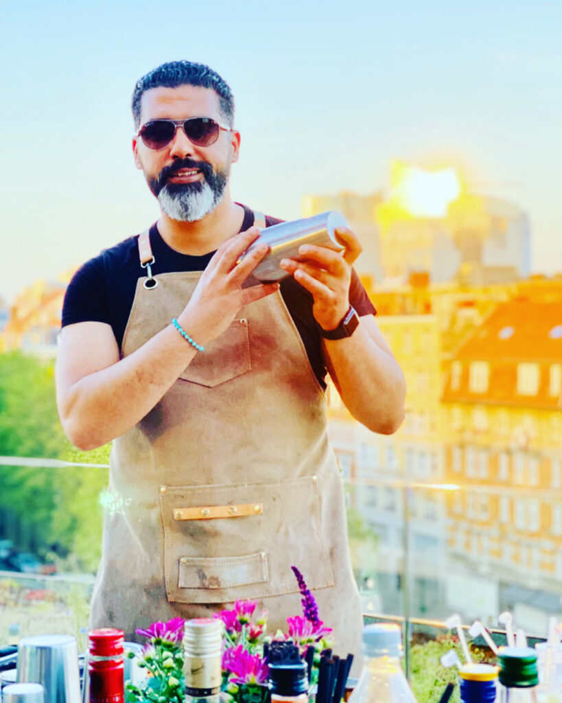 Barman préparant un cocktail sur rooftop au coucher du soleil, ambiance élégante avec vue sur la ville