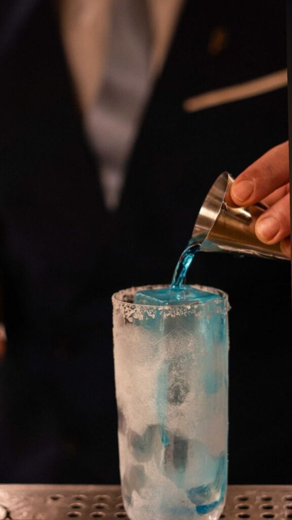 Cocktail premium bleu versé dans verre givré avec glace et bord salé