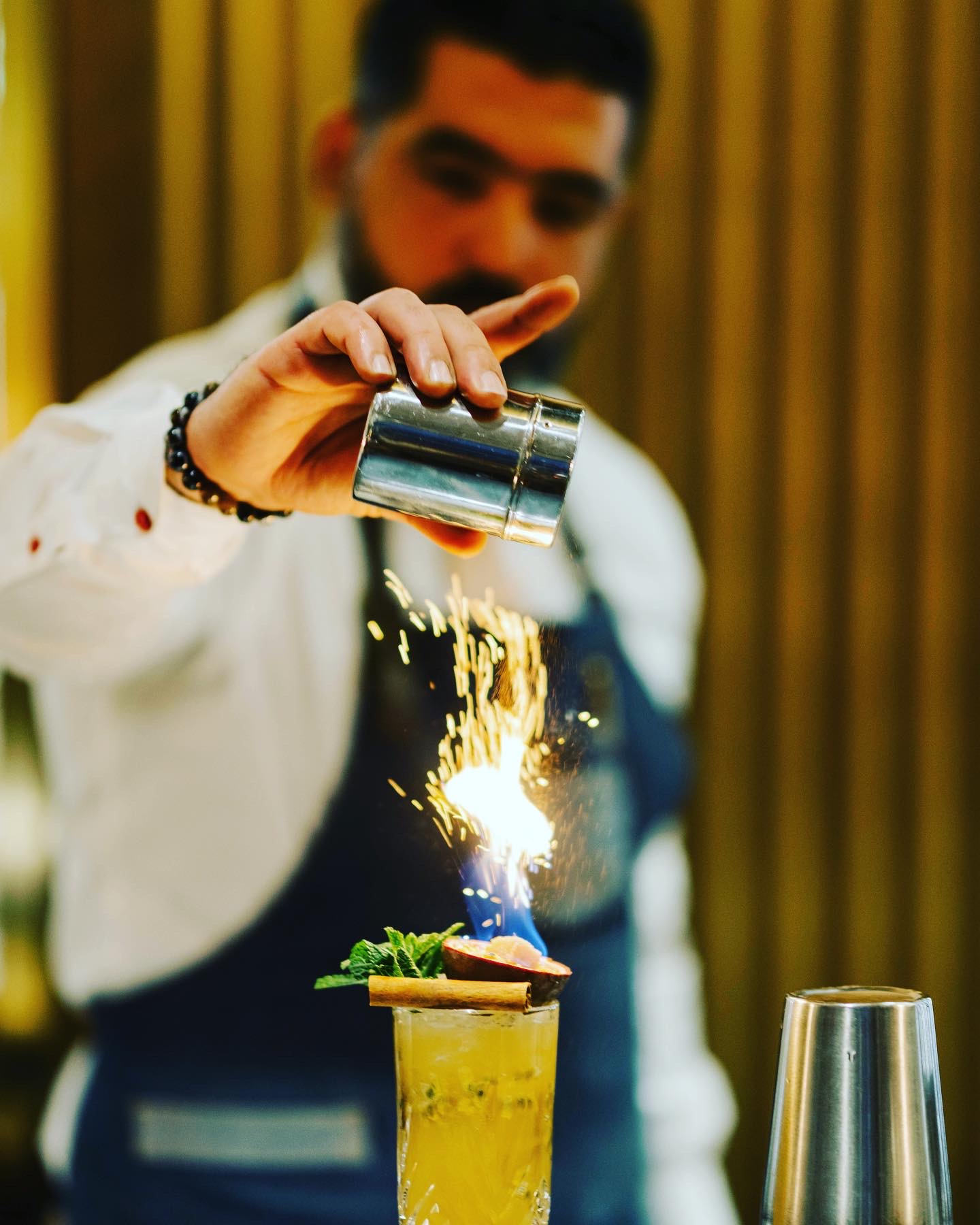 Bartender Nomad Bar préparant un cocktail flambé avec étincelles
