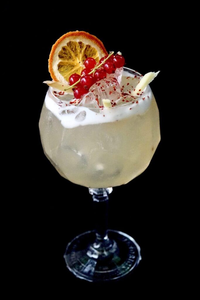 Cocktail premium Nomad Bar jaune avec orange séchée et groseilles