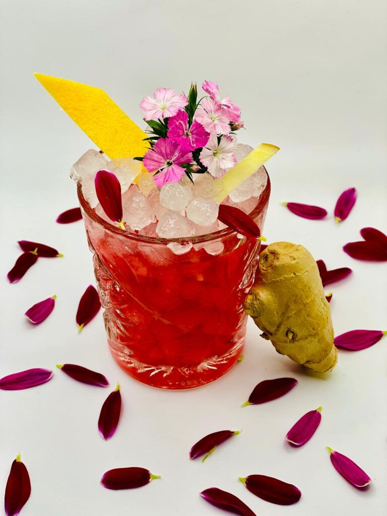 Cocktail premium rouge avec agrume, fleurs et gingembre