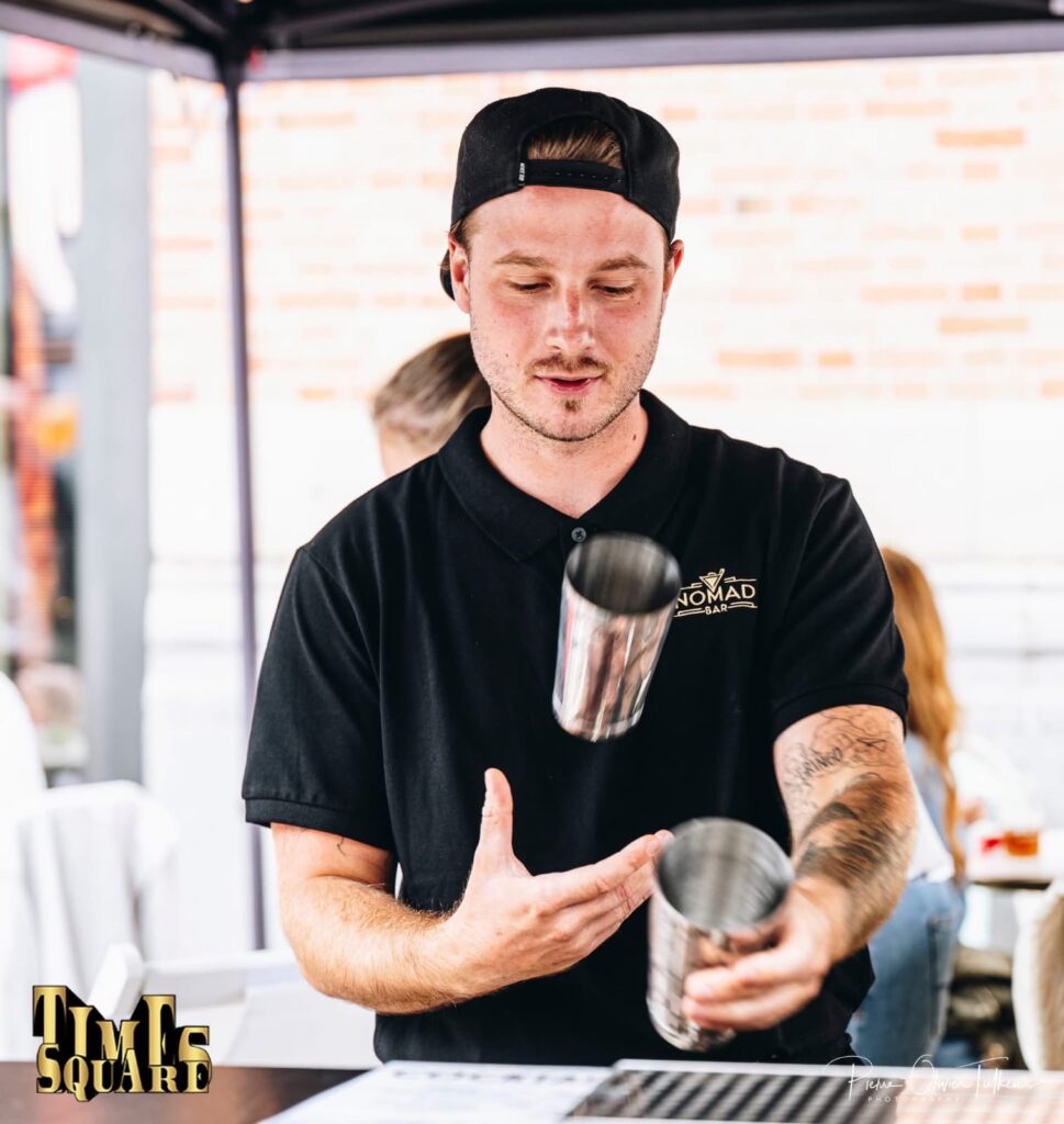 Bartender Nomad Bar réalisant un flair avec deux shakers en extérieur