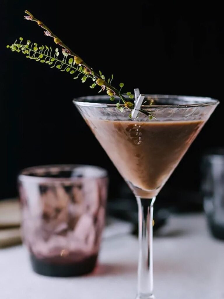 Cocktail signature servi dans un verre Martini avec garniture végétale