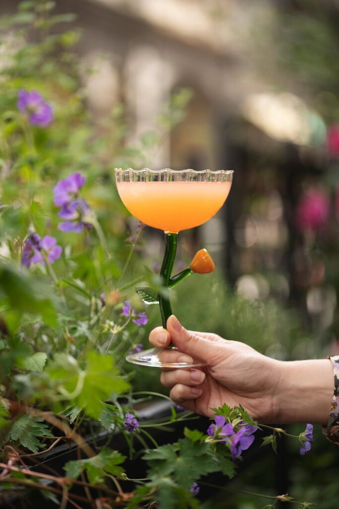 Cocktail signature orangé présenté dans un décor végétal
